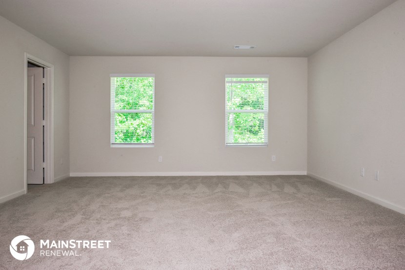 an empty room with two windows and a door