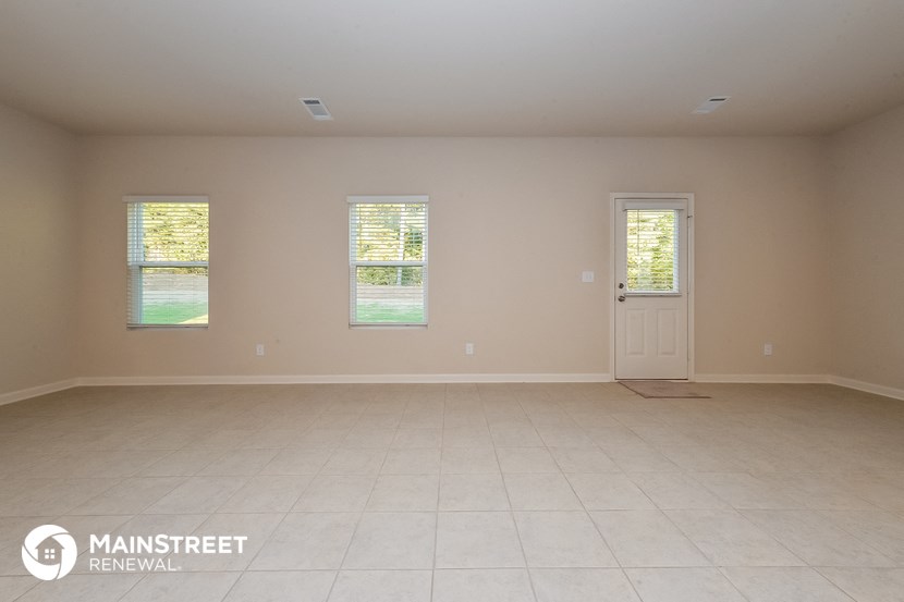 an empty room with a door and three windows