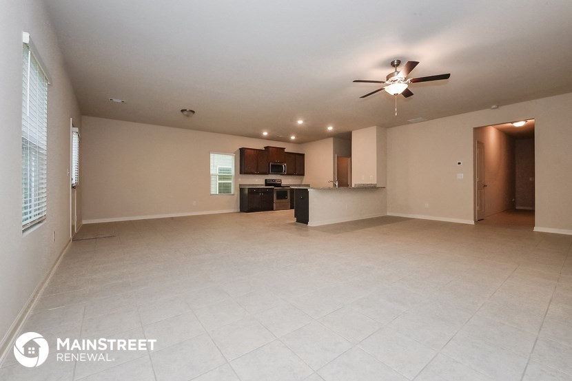 an empty living room and kitchen with a ceiling fan