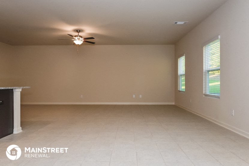an empty living room with a ceiling fan