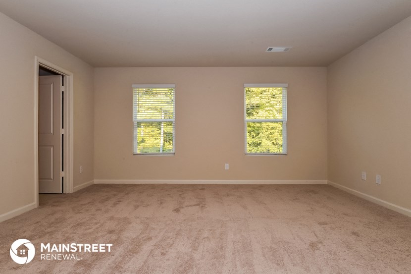 the interior of an empty room with a door and two windows