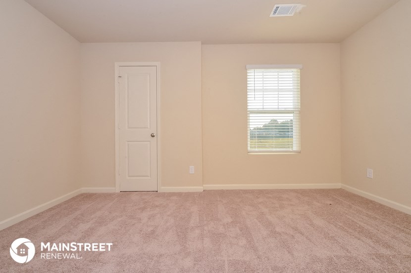the upstairs bedroom with carpet and a white door and window