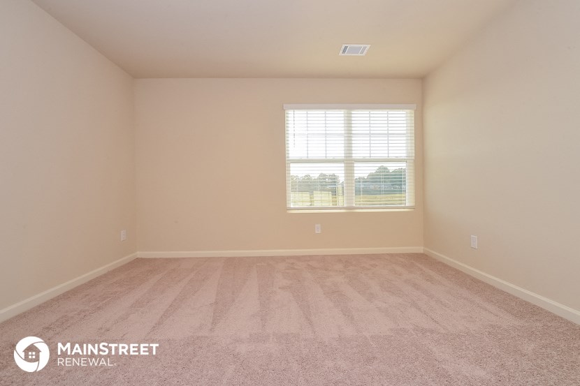 the spacious living room with carpeting and a window