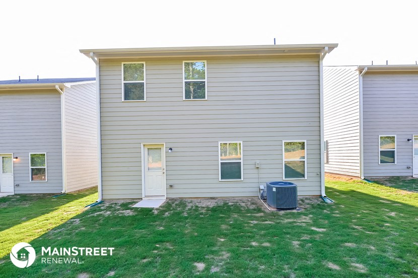the exterior of a white house with a yard in front