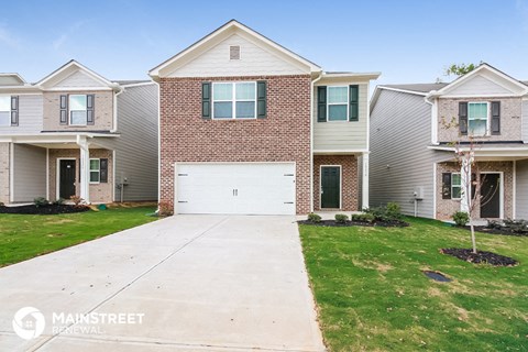 a brick house with a white garage door in front of a green lawn