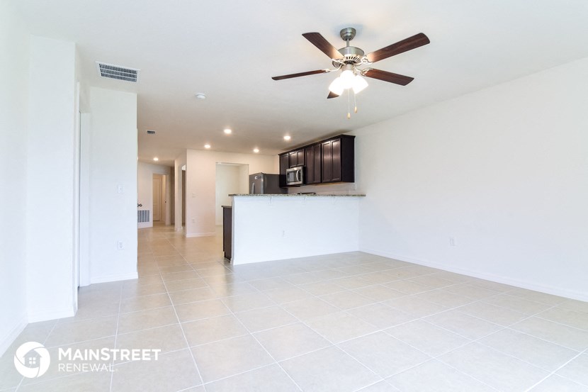 a kitchen and living room with white tile flooring and a ceiling fan
