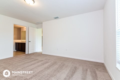 a spacious living room with white walls and carpet