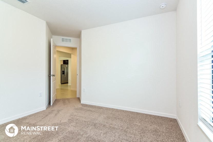 a spacious living room with white walls and carpet