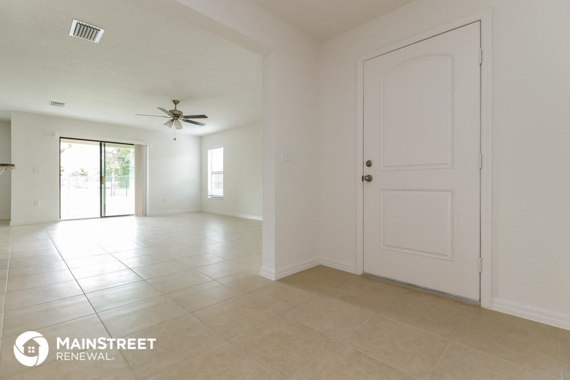 an empty living room with a white door and tile floor