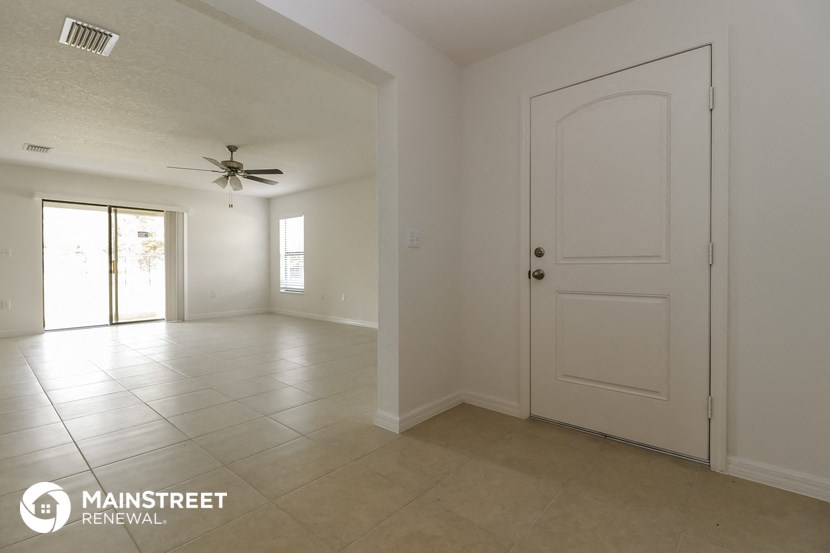 an empty living room with a white door and a ceiling fan