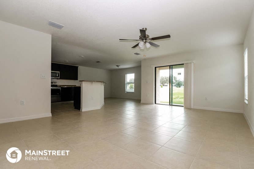 a spacious living room with tile flooring and a ceiling fan