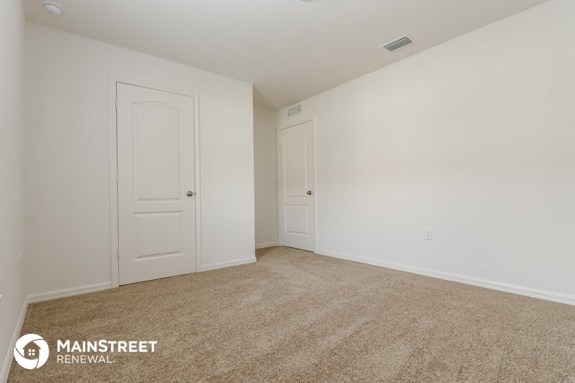 the spacious living room of an apartment with white walls and carpet