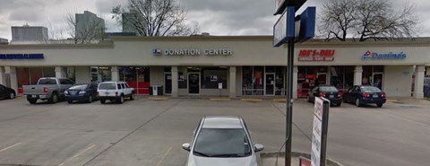 A white car is parked in front of a donation center.