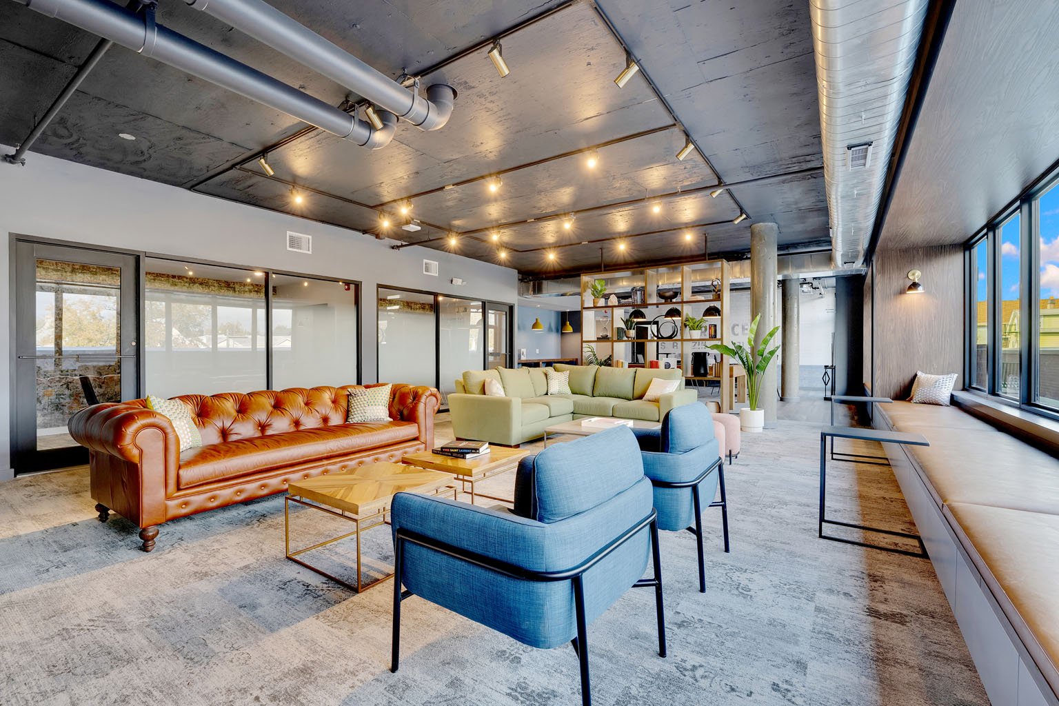 A modern living room with a brown leather sofa and blue armchair.