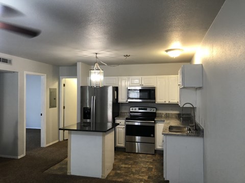 A kitchen with white cabinets and a black countertop.