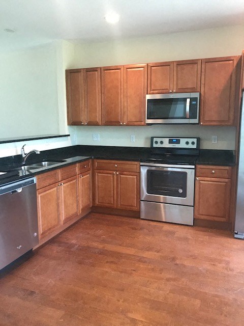 A kitchen with wooden cabinets and black countertops.