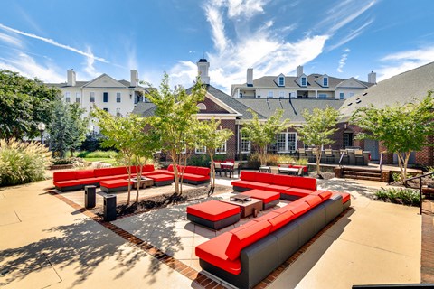 a lounge area with red couches and tables in a courtyard