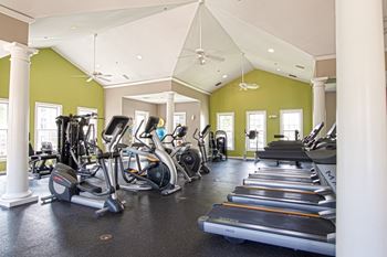24-hour fitness studio with ellipticals, treadmills, bikes, weight machines, and free weights