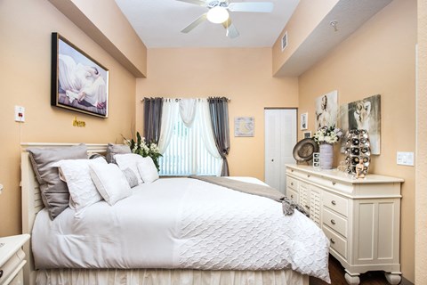 bedroom with fan, large window, and model furnishings
