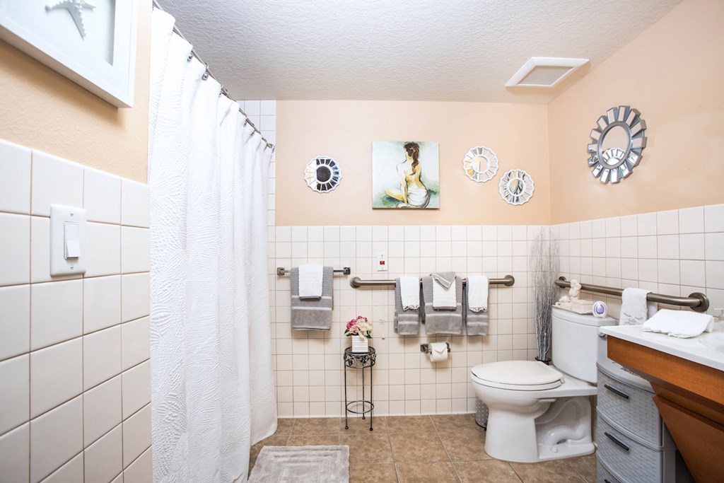 bathroom with handrails, tile, and low entry shower