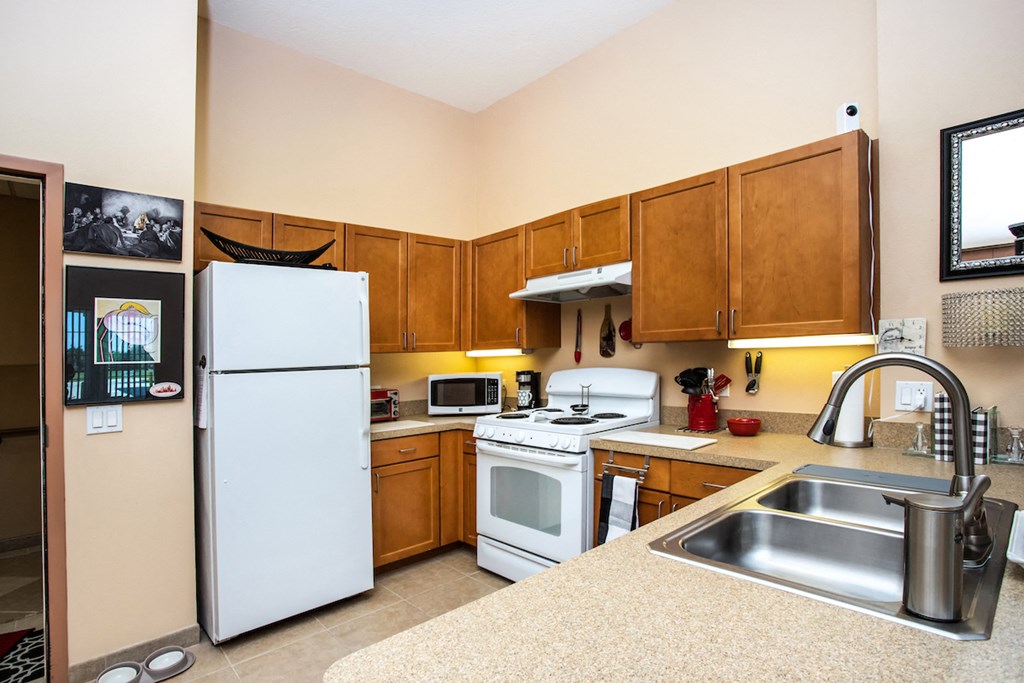 kitchen with stainless steel sink, white appliances, and wood cabinets