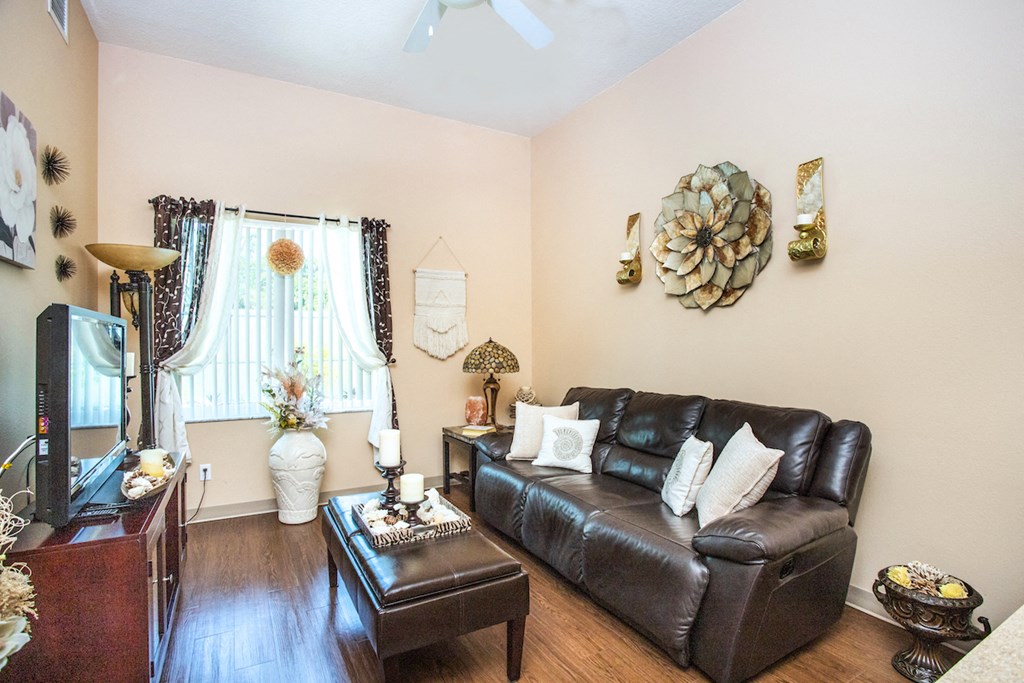 living room with plank-style floors, large window, and fan