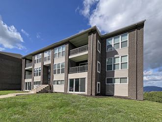 a brick apartment building with green grass and a blue sky