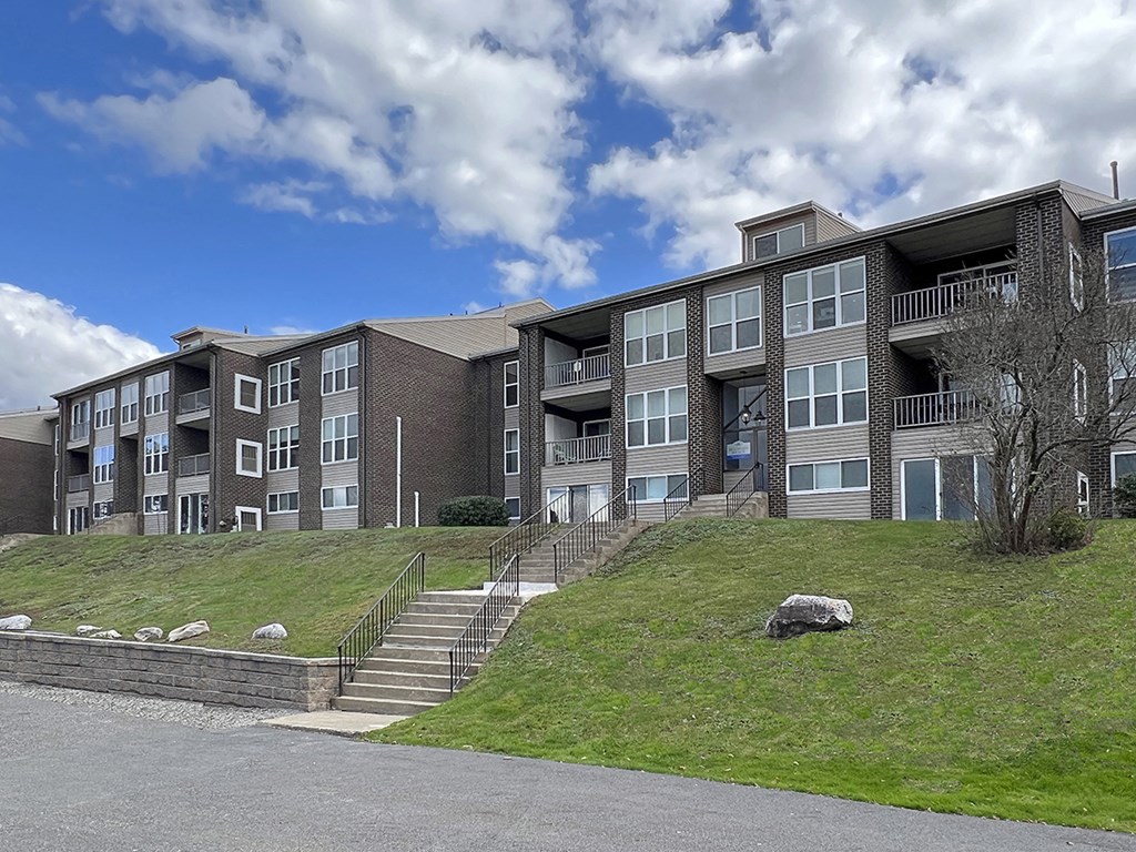a large apartment building on a hill with grass