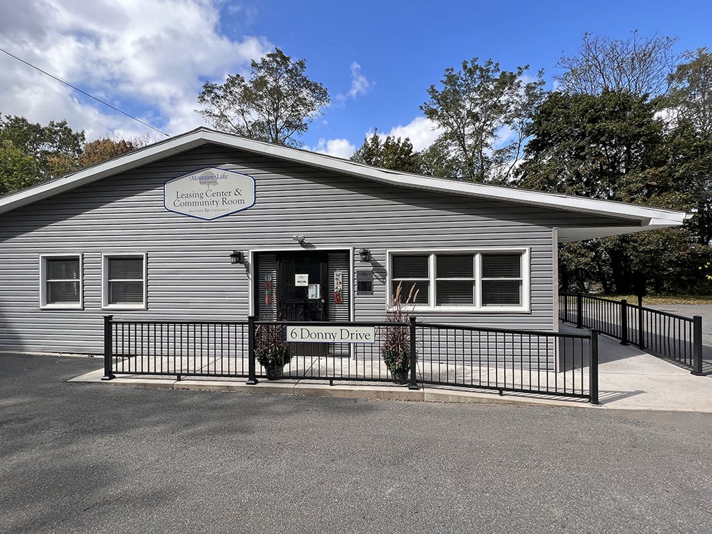 a gray building with a fence and a sign on the front of it