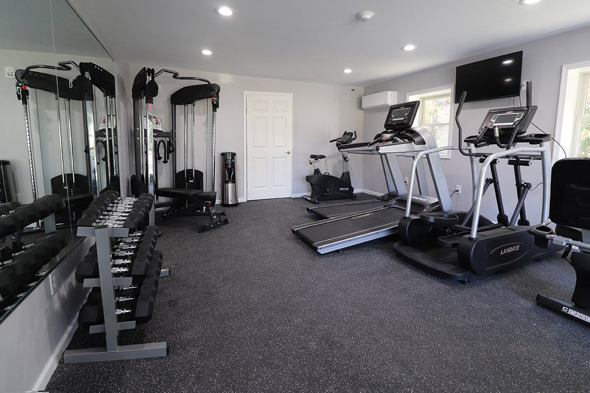 a gym with cardio equipment and a tv