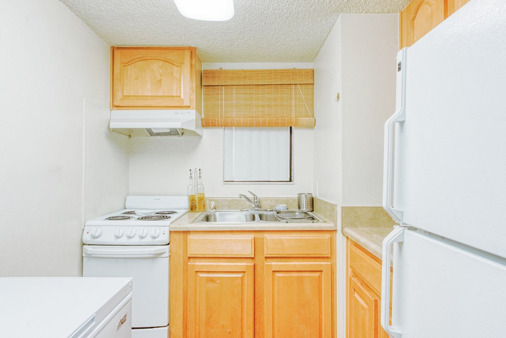 kitchen with white appliances, double stainless steel sink, and wood cabinetry