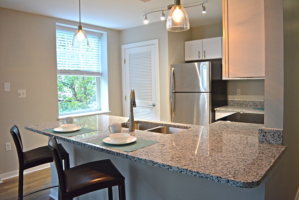 Kitchen with quartz island, pendant light and large window at Residences at Forest Park, Saint Louis, MO