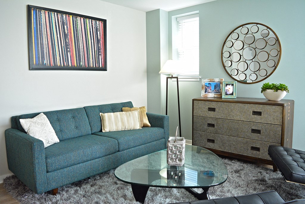 living room with gray rug , blue couch, and wood dresser at Residences at Forest Park, Saint Louis