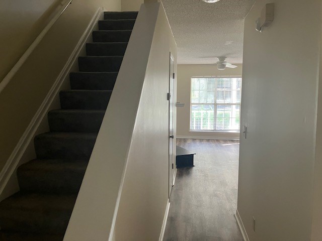 A hallway with a staircase and a door leading to a balcony.