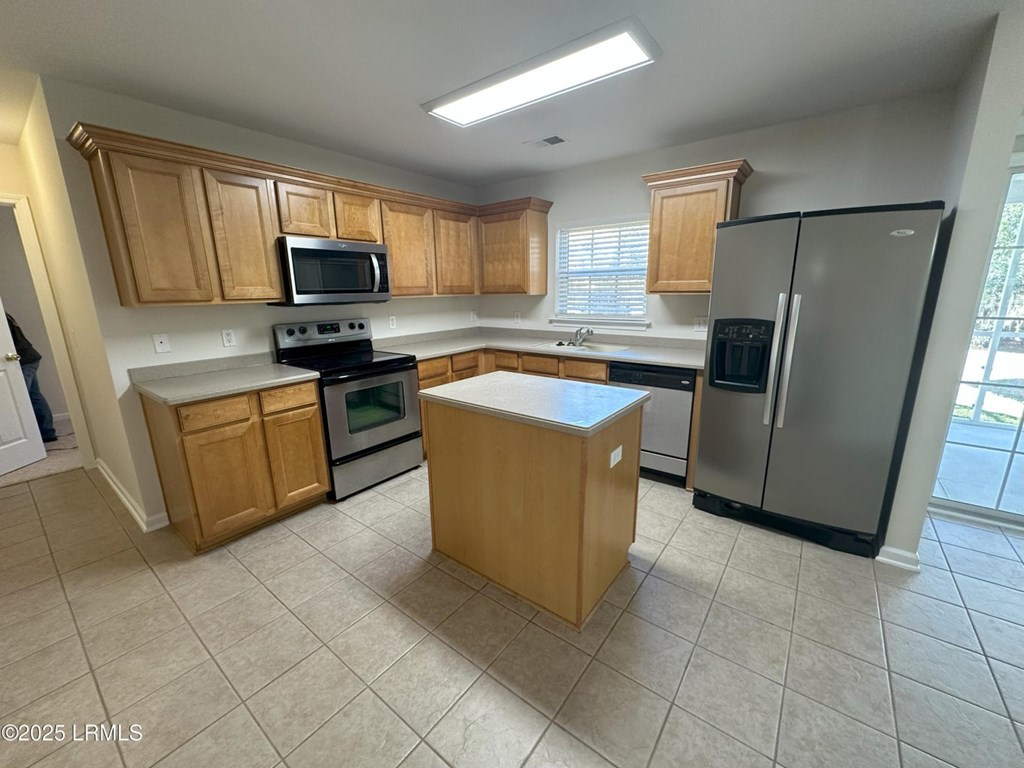 A kitchen with wooden cabinets and a black refrigerator.