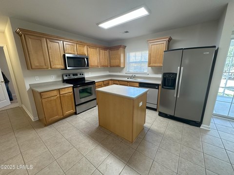 A kitchen with wooden cabinets and a black refrigerator.