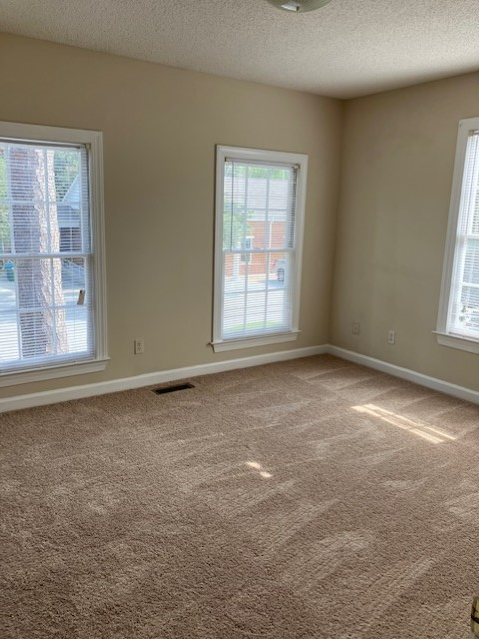 an empty living room with two windows and a carpeted floor