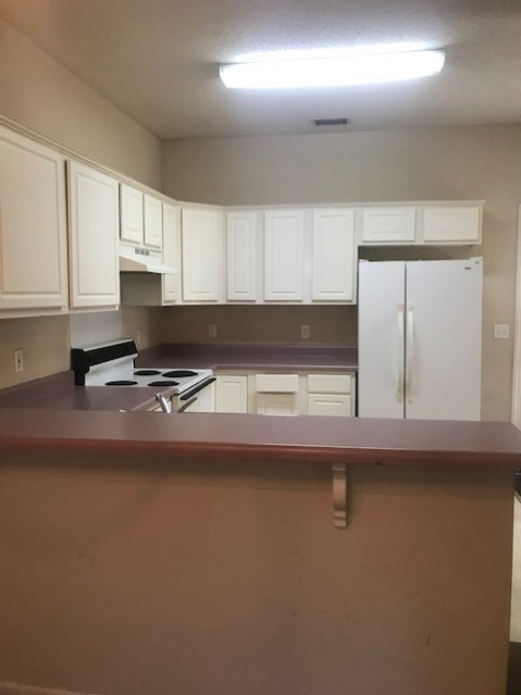 an empty kitchen with white cabinets and a counter top