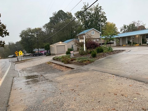 A wet street with a yellow sign on the side.