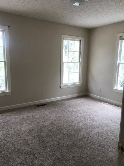 an empty room with two windows and a carpeted floor