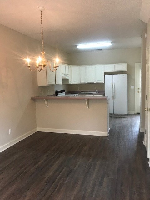 an empty living room and kitchen with white cabinets