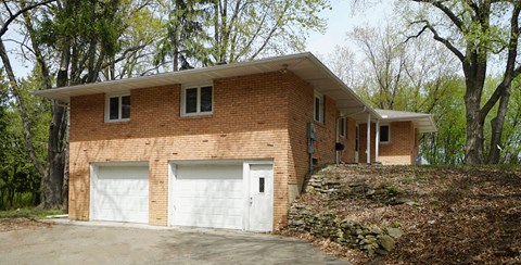 A two-story house with a garage is surrounded by trees.