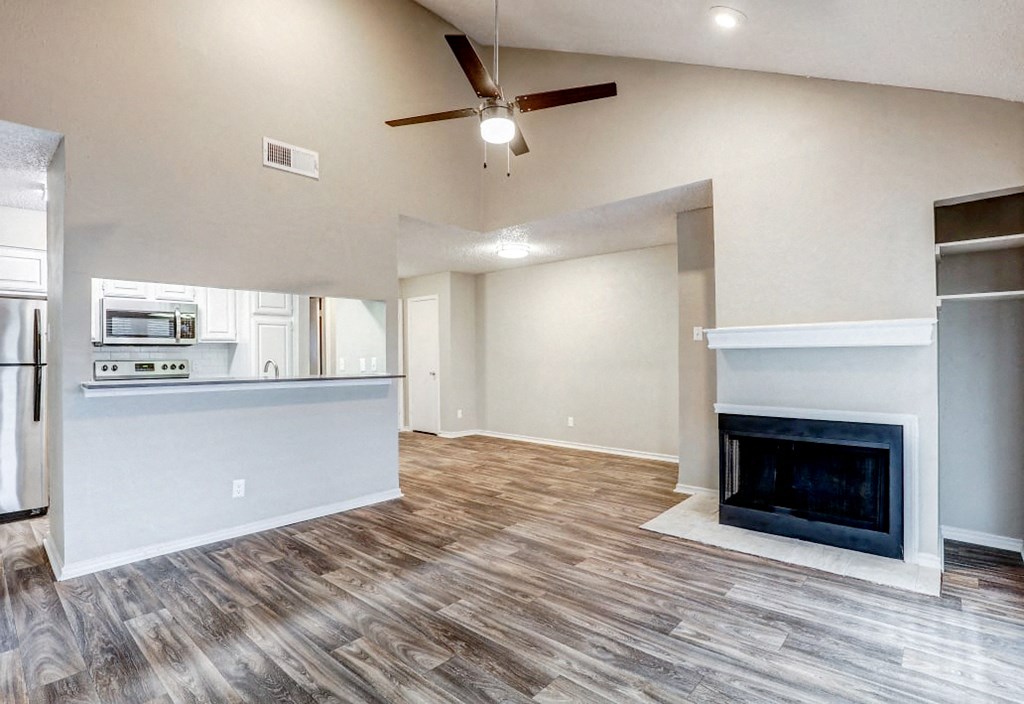 an empty living room with a fireplace and a kitchen