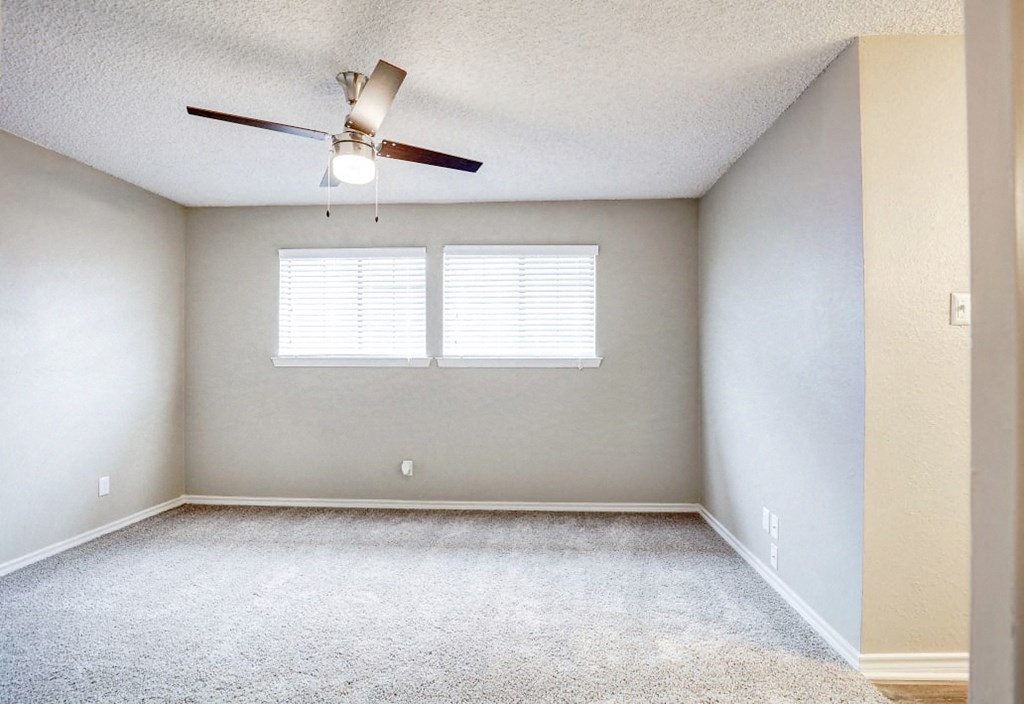 an empty room with a ceiling fan and a window