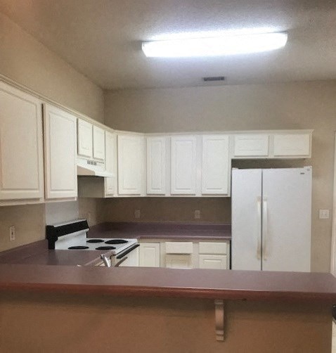 an empty kitchen with white cabinets and a counter top