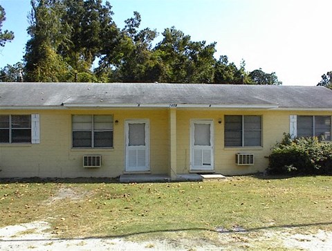 A yellow house with a grey roof and white doors and windows.