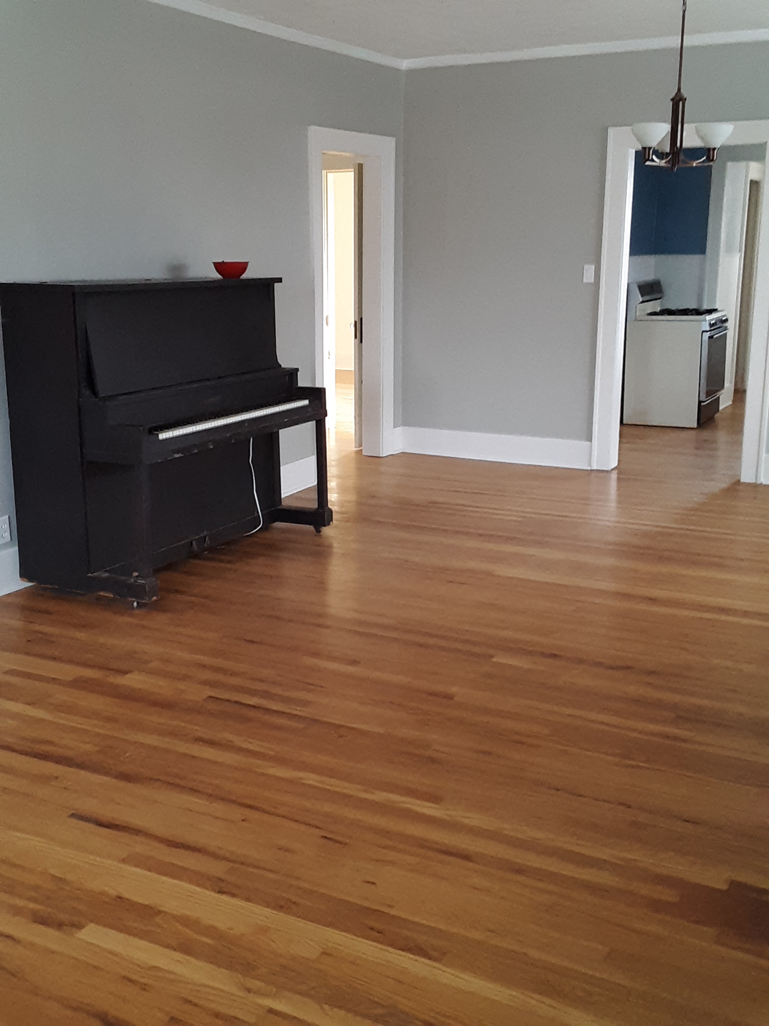 A black piano sits in a room with wooden floors.