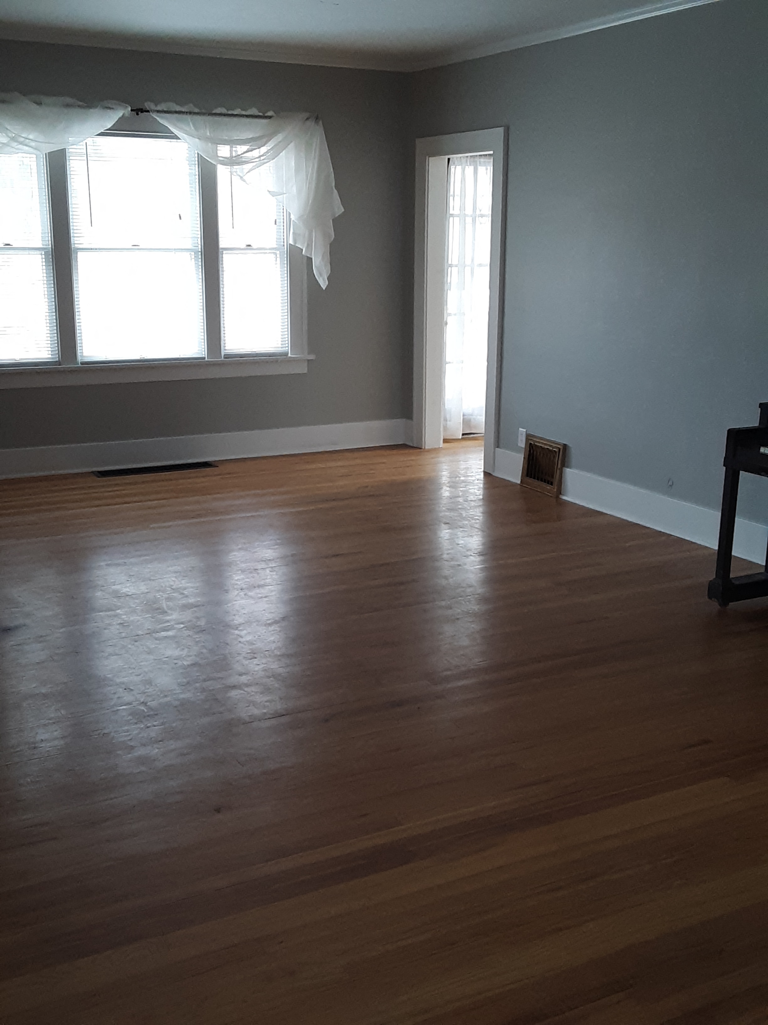 A room with wooden floors and a window with curtains.