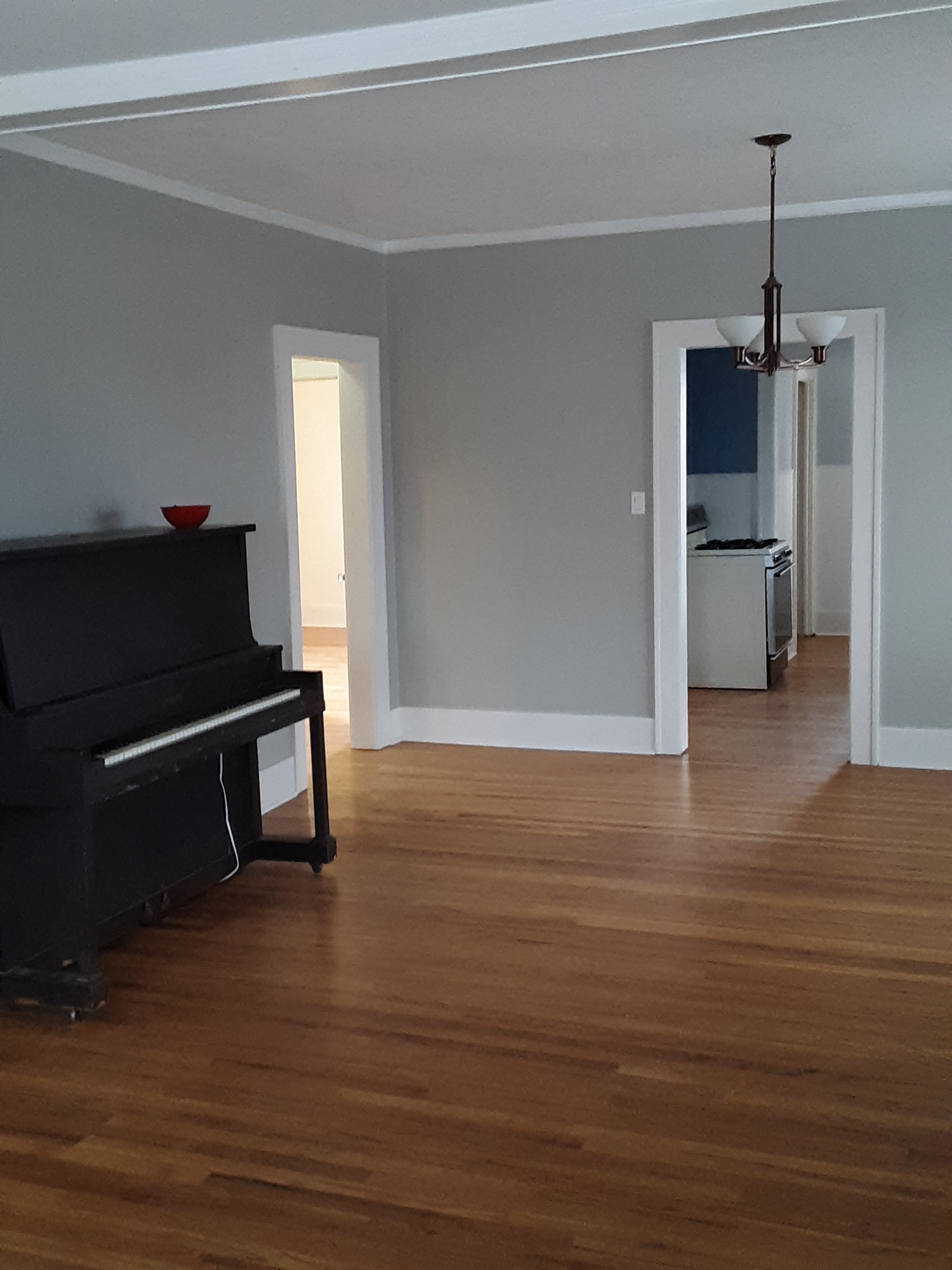 A black piano sits in a room with wooden floors and white walls.