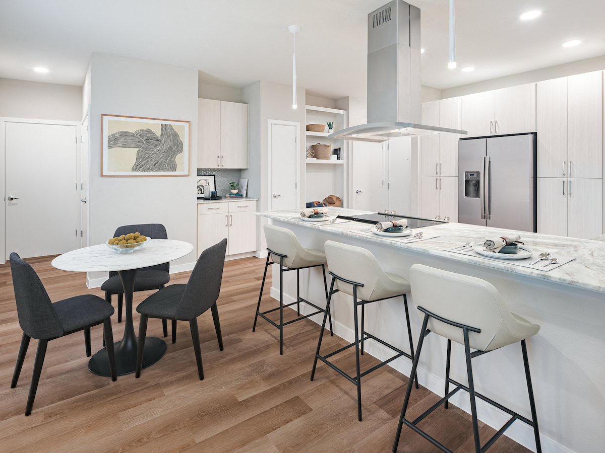 A modern kitchen with a white table and black chairs.